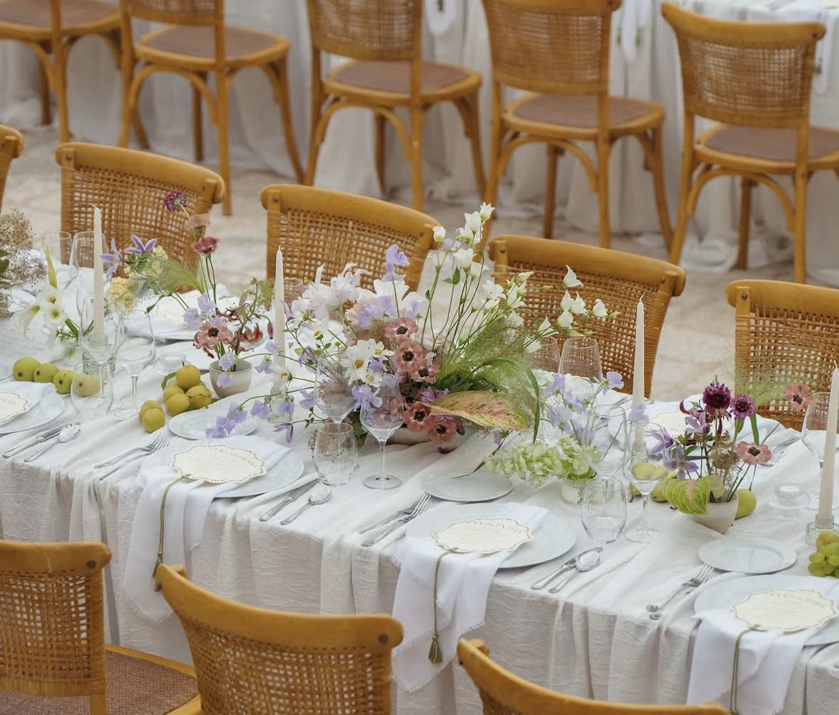 Tablescape with wildflowers, candles, and citrus among rattan chairs